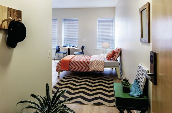 Each studio apartment contains a kitchenette, a bathroom, a bed, a table, chairs, and a move-in kit with pots, pans, sheets, blankets, pillows, a broom, and other amenities.