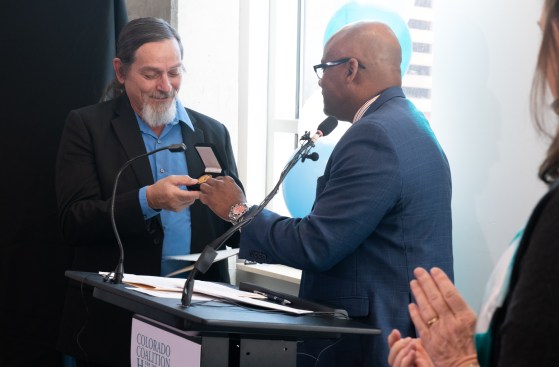 Mayor Michael B. Hancock presents John Parvensky with a city coin, the highest honor for people who make extraordinary differences in the Denver community.