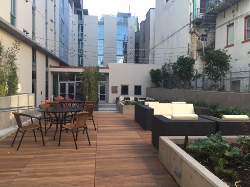 The development includes a kitchen, a community room, and outdoor space, including barbecues and a resident garden.