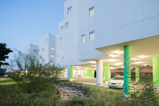 Except for where it touches down in the front and back of the site, the entire building is lifted off the ground, which creates an expansive landscape that stretches across the site and restores the ground plane as a native field supporting multiple outdoor uses, including car and bike parking, community gardens, and barbecue patio areas.