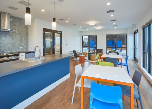 Amenities include an event room with a kitchen, a business center with computers, a fitness center, and a ground-level courtyard. 